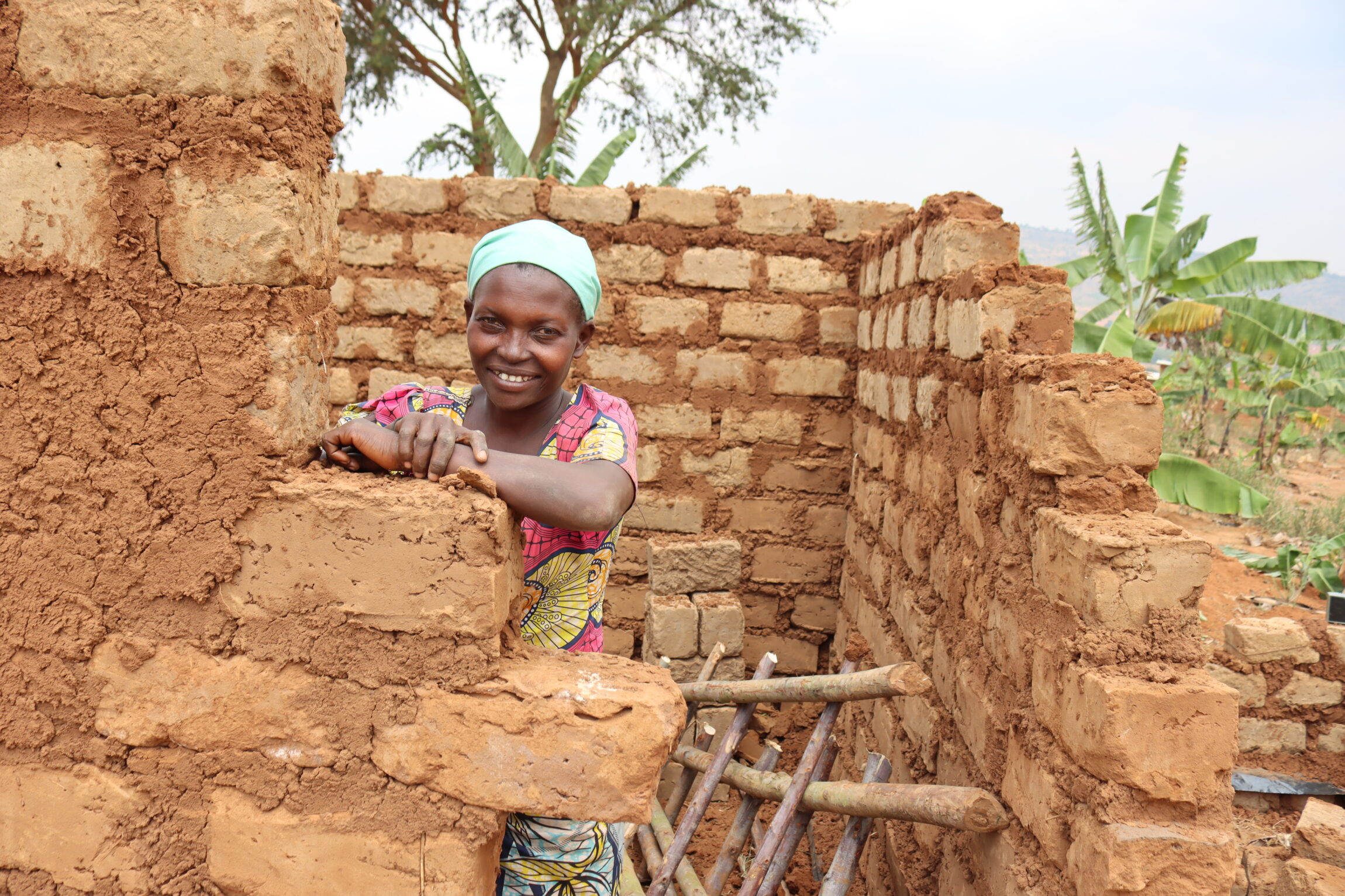 Nikuze Uwimana, a refugee from the Democratic Republic of Congo (DRC), stands inside her house under construction, supported by TPO Uganda and DCA.